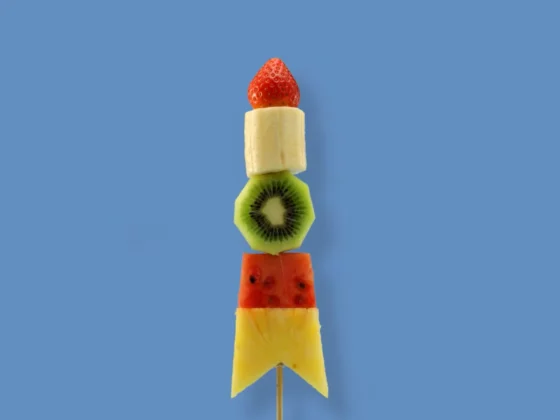 Still frame from our social content for Actimel: 'Real Fruit Rocket'. Skewer of fruit in the shape of a rocket against a sky blue background.