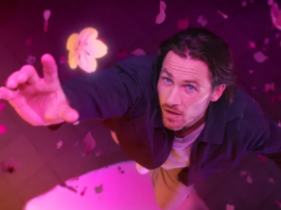 Still frame from 'Master the Market Forces' City Index TVC. Man surrounded by pink light and petals jumps into the air to catch a flower.