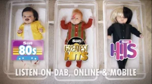 Still frame from our 'Born to Party' TVC for The Scottish Sun. Top down view of 3 babies in hospital cribs. The baby on the left is dressed as Freddie Mercury, with the logo for 'Scottish Sun 80's' over them. The middle baby is dressed as David Bowie, with the logo for 'Sun Greatest Hits' over them. The right baby is dressed as Sia, with the 'Sun Hits' logo over them. The tagline across the bottom reads 'Listen on Dab, Online & Mobile'.