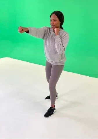 One of the fitness instructors performing a punching move in front of a green screen.