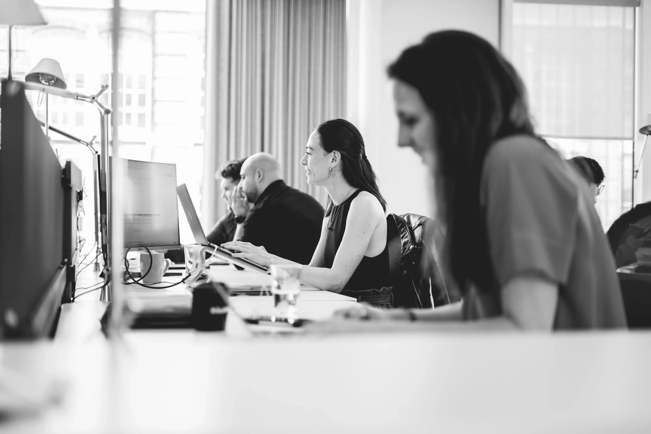 Black and white photo of the Pebble team working hard at their desks in our open plan office.